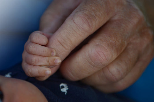 My newborn baby holding my dads hand